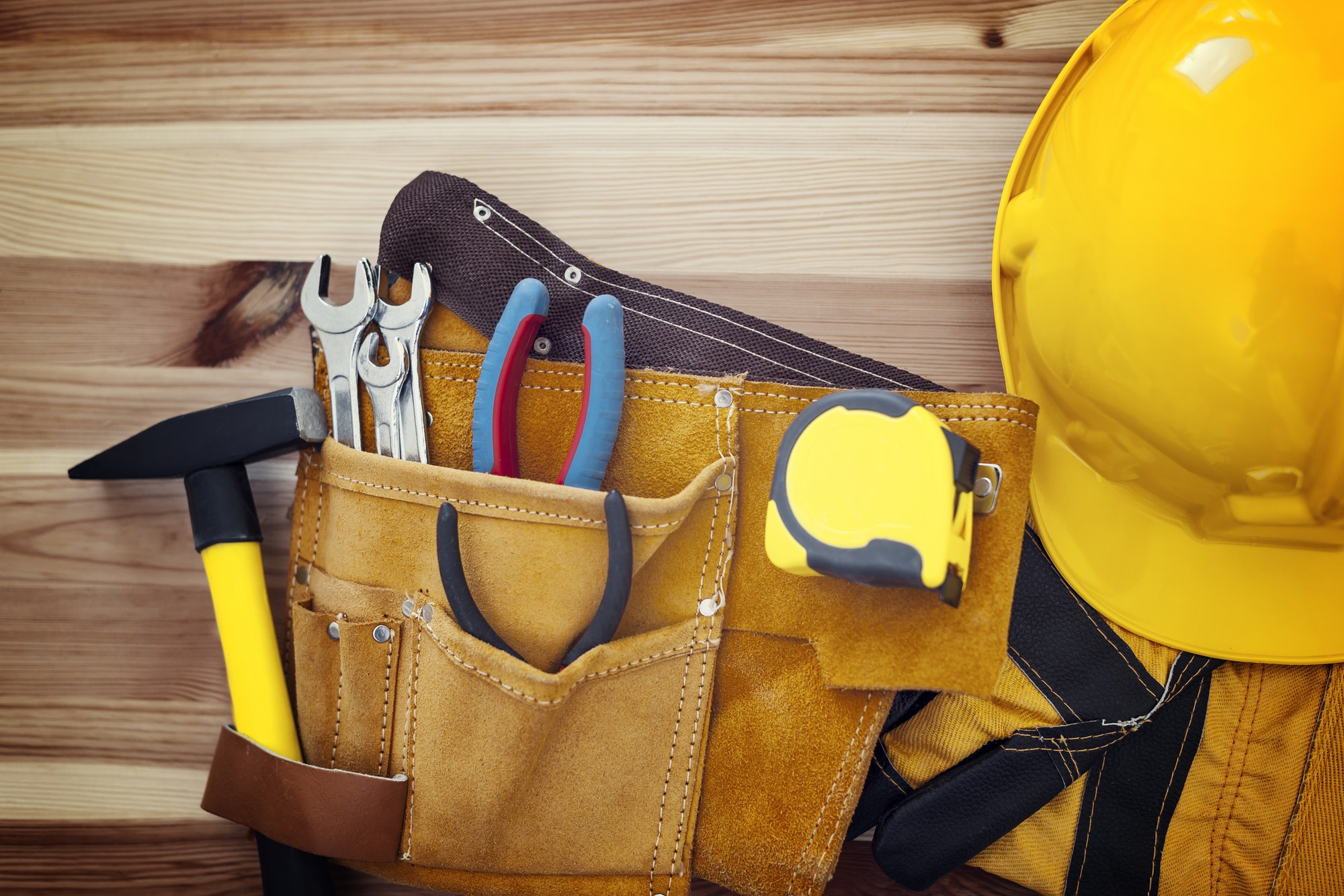 Belt with tools and yellow helmet on wood