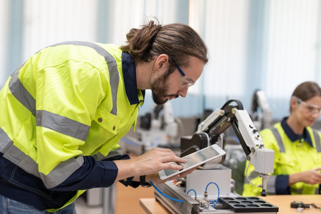 Male engineer using remote testing and control AI robot model in academy robotics laboratory room