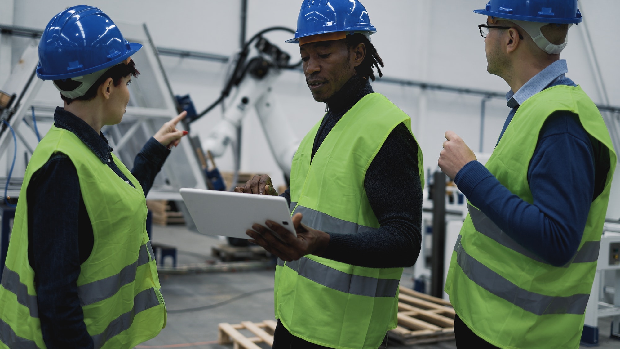 Team of engineers working in robotic factory monitoring the project on the tablet